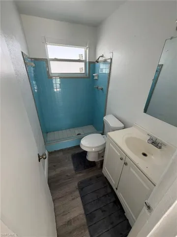 Full bath with a stall shower, vanity, and dark wood-style flooring