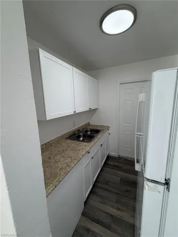 Kitchen featuring freestanding refrigerator, white cabinetry, and dark wood-style flooring