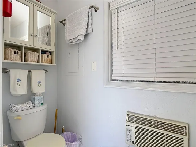 Half bathroom with toilet and an AC wall unit