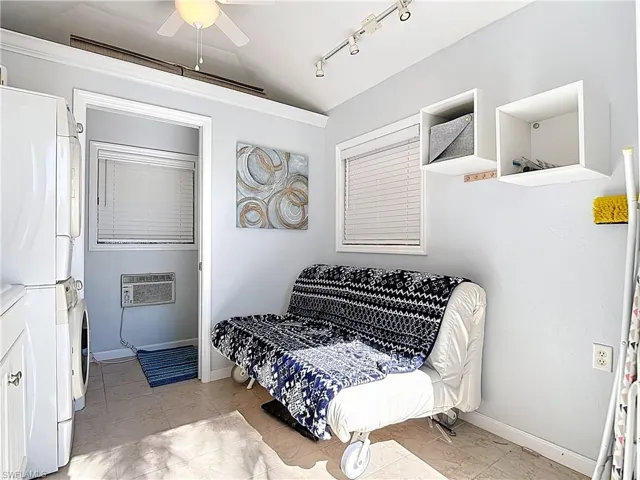 Bedroom featuring track lighting, lofted ceiling, ceiling fan, estacked washer and dryer, and light tile patterned floors