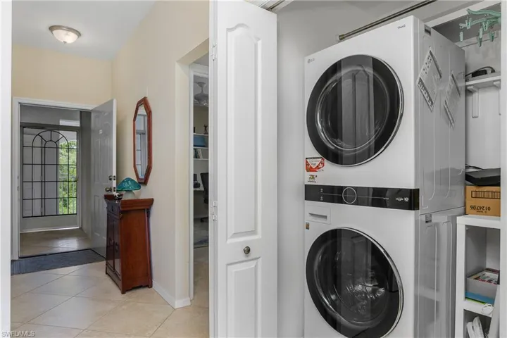 Washroom with laundry area, stacked washer and dryer, baseboards, and light tile patterned floors