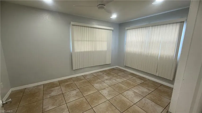 Tiled empty room featuring baseboards and ceiling fan