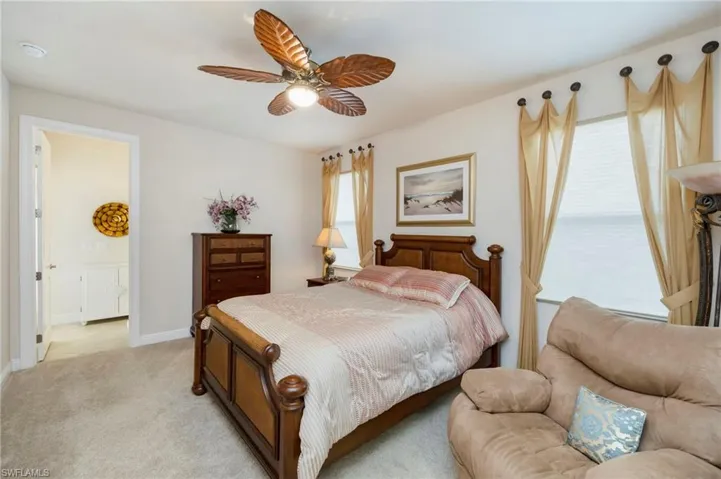 Carpeted bedroom with ceiling fan and ensuite bathroom