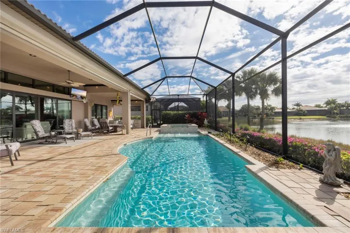 View of swimming pool featuring a patio area, glass enclosure, a sunroom, and a pool with connected hot tub