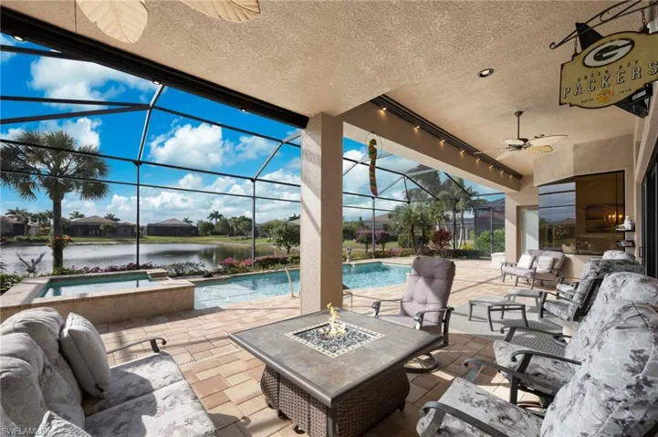 View of patio / terrace with a ceiling fan, an outdoor living space with a fire pit, a sunroom, a lanai, and a water view