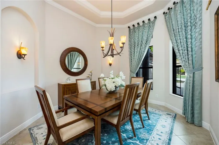 Dining room featuring crown molding, a raised ceiling, and a chandelier