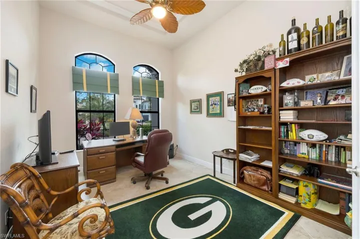 Office space with a ceiling fan, light tile patterned floors, and a towering ceiling