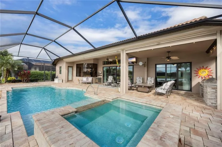 View of pool with a patio, a sunroom, area for grilling, glass enclosure, and a pool with connected hot tub