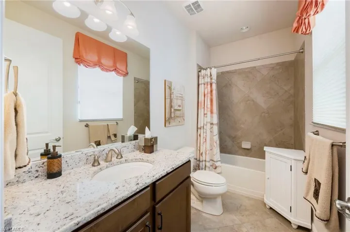 Full bath featuring vanity, shower / bath combo, and light tile patterned flooring
