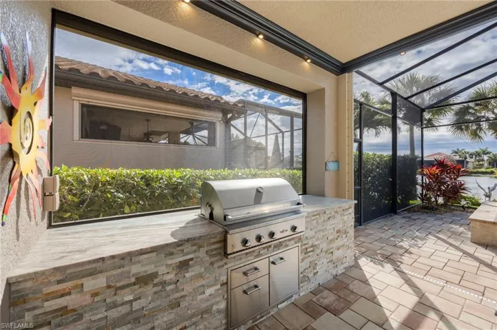 View of patio / terrace featuring glass enclosure, an outdoor kitchen, and a sunroom