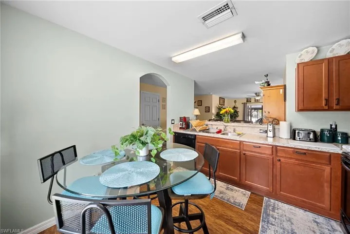Kitchen featuring light countertops, dark wood-style floors, arched walkways, wood finish cabinets, and a peninsula