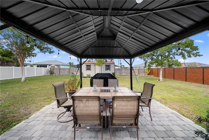 Fenced backyard featuring a patio area, outdoor dining area, grilling area, and an outbuilding