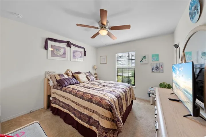 Bedroom with a ceiling fan and light colored carpet
