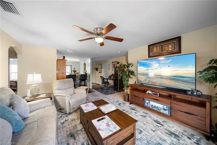 Living area featuring arched walkways and a ceiling fan