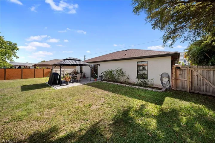 Rear view of property with a patio area, a gate, a fenced backyard, a gazebo, and stucco siding
