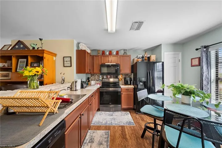 Kitchen featuring black appliances, wood finish cabinetry, and light wood-style flooring