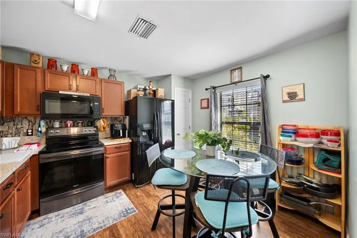 Kitchen featuring black appliances, wood finish cabinets, light wood-style floors, and backsplash