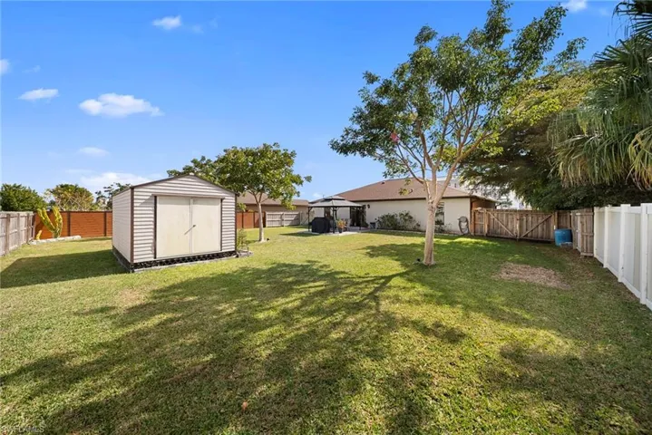 Fenced backyard featuring a storage shed and a gate
