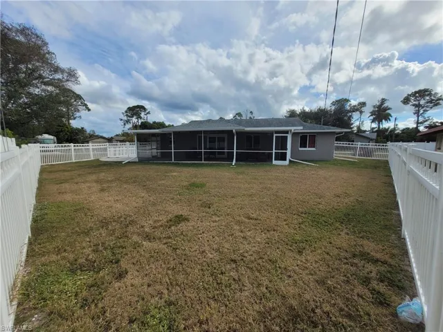 Back of house featuring a fenced backyard, a sunroom, and stucco siding