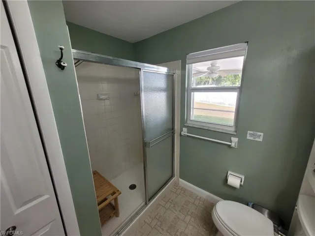 Full bath featuring a shower stall and toilet