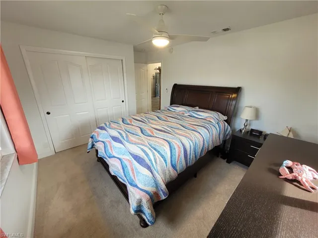 Bedroom with light carpet, a closet, and a ceiling fan