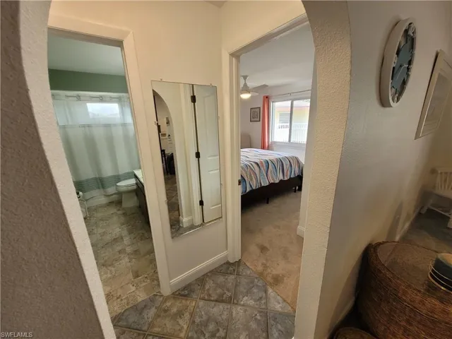 Corridor with a textured wall, arched walkways, tile patterned floors, and carpet flooring