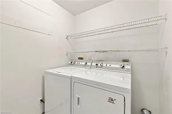 Laundry area with a top-load washer, front-load dryer, and two wall-mounted wire shelves