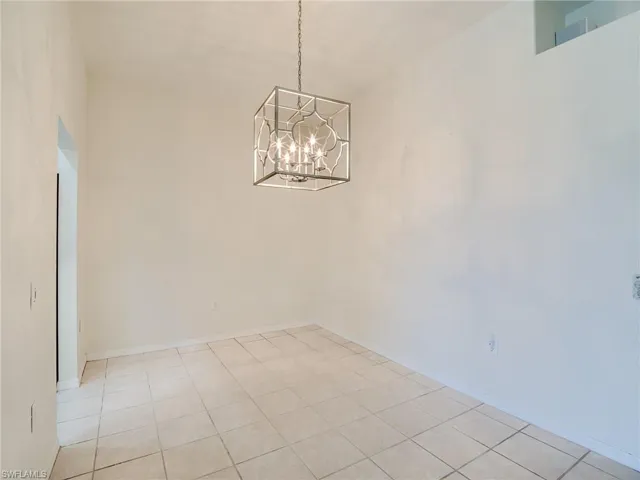 Unfurnished dining area with a towering ceiling, an inviting chandelier, and light tile patterned floors