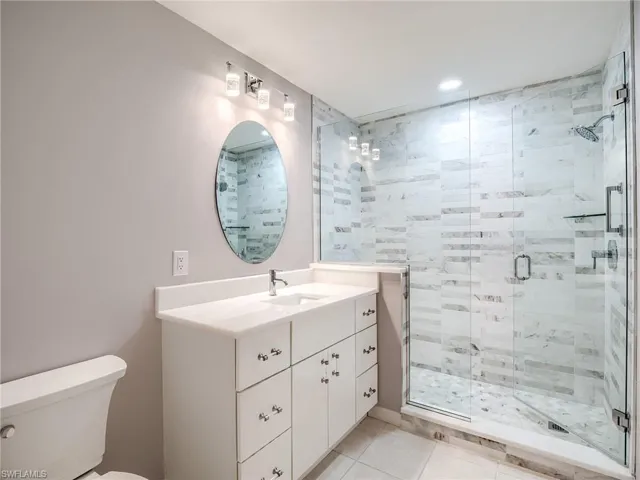 Bathroom featuring a shower with shower door, toilet, vanity, and tile patterned floors