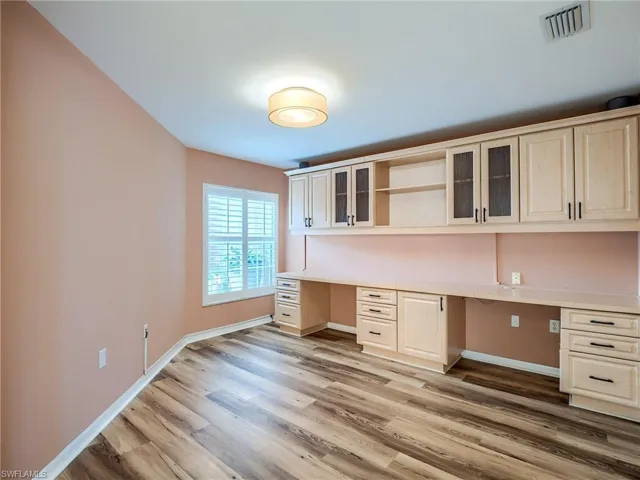 Unfurnished office featuring light hardwood / wood-style floors and built in desk
