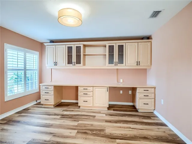Unfurnished office with light hardwood / wood-style flooring and built in desk