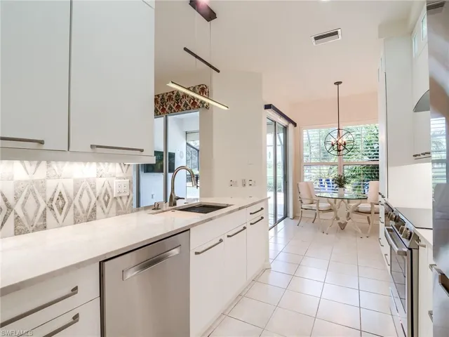 Kitchen featuring white cabinetry, appliances with stainless steel finishes, sink, and hanging light fixtures