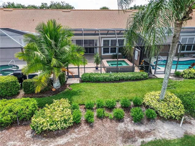 View of yard with glass enclosure, a patio area, and a swimming pool with hot tub