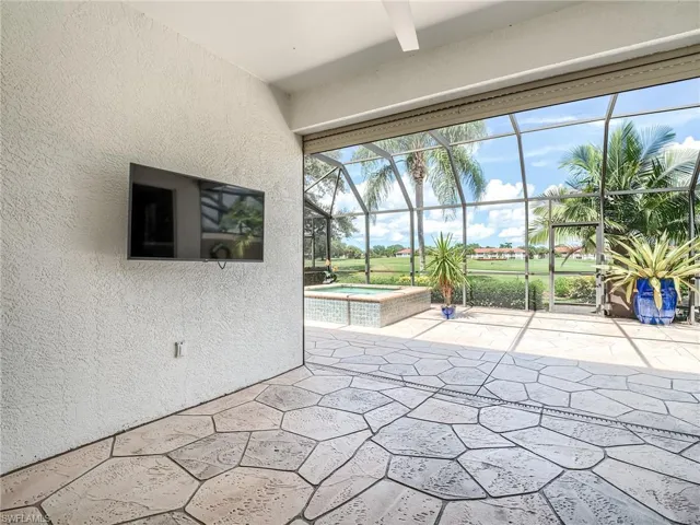 View of patio featuring glass enclosure and an in ground hot tub