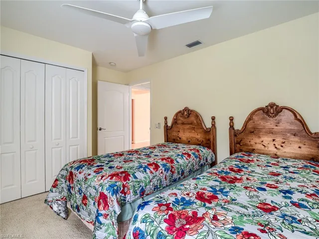 Carpeted bedroom featuring ceiling fan and a closet