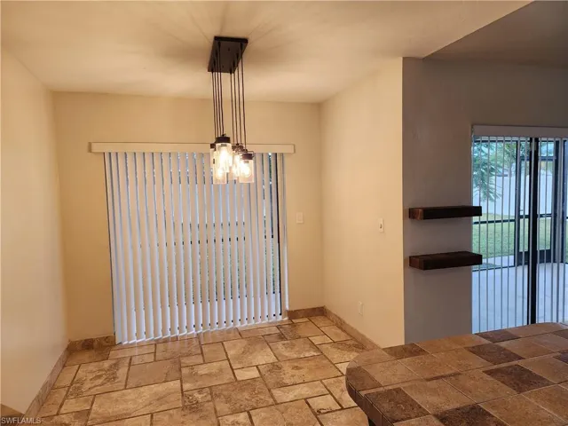Unfurnished dining area with stone tile flooring and baseboards