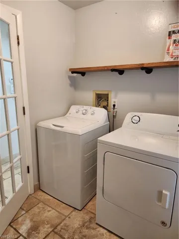 Laundry area featuring washing machine and clothes dryer and stone tile flooring