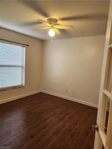 Spare room featuring dark wood-type flooring and ceiling fan