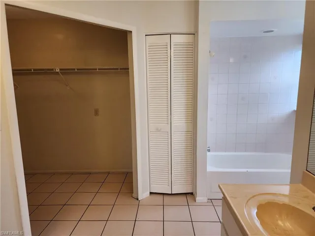 Bathroom with a closet, tile patterned floors, vanity, and bathing tub / shower combination