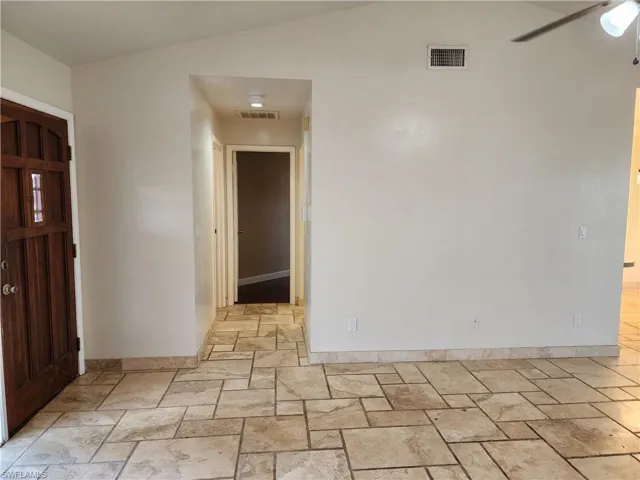 Entryway with stone tile floors, ceiling fan, and lofted ceiling