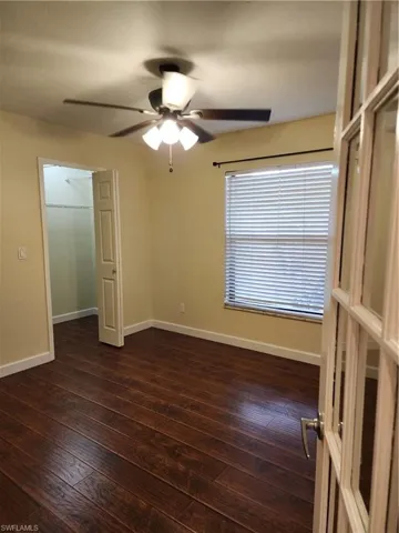 Unfurnished bedroom featuring dark wood-type flooring and a ceiling fan
