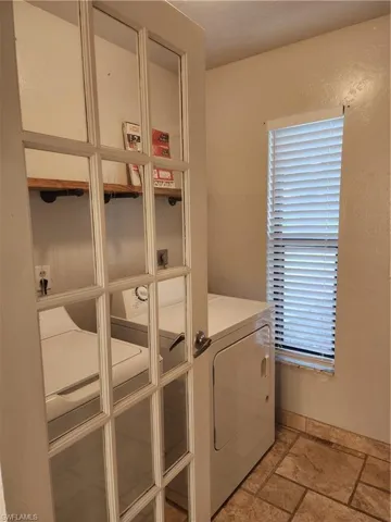 Washroom featuring stone tile floors and washer and clothes dryer