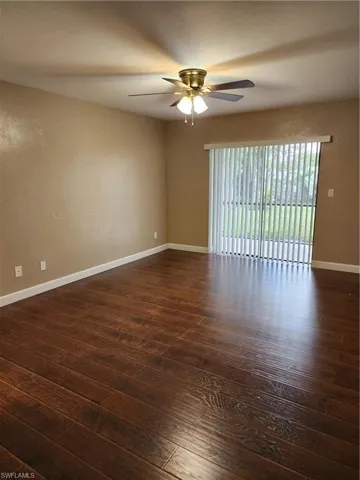 Spare room with dark wood-type flooring and ceiling fan