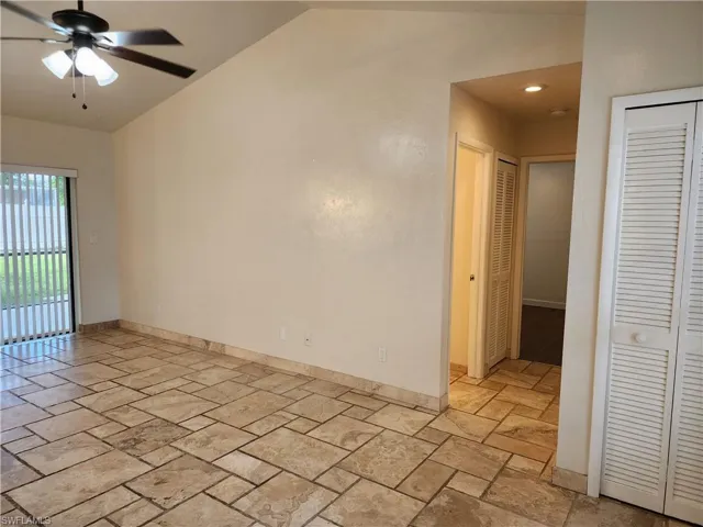 Unfurnished room featuring stone tile flooring, a ceiling fan, and vaulted ceiling