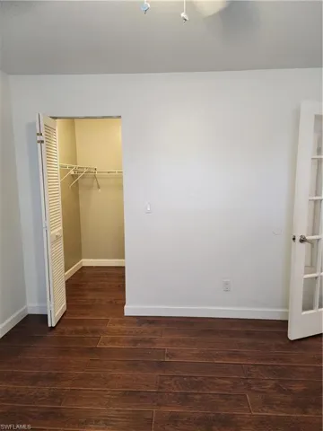 Unfurnished bedroom featuring dark wood-style floors and a spacious closet