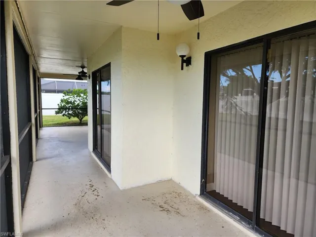 Doorway to property with a ceiling fan and stucco siding