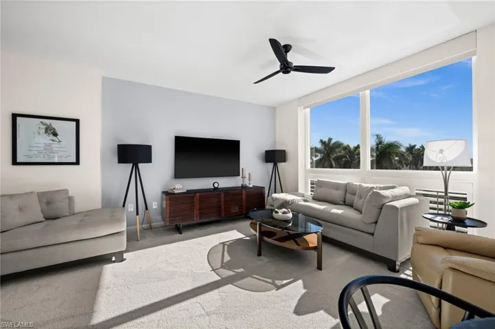 Carpeted living area featuring ceiling fan