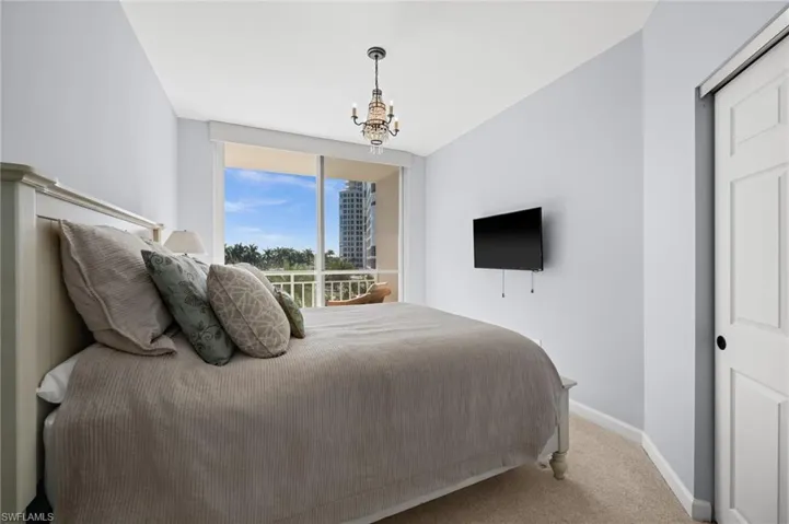Carpeted bedroom with baseboards and a chandelier