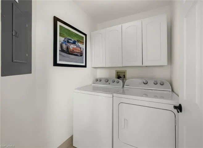Washroom featuring electric panel, cabinet space, and washer and dryer