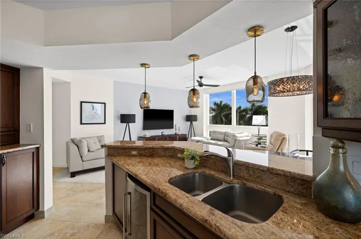 Kitchen with open floor plan, hanging light fixtures, and dark stone counters